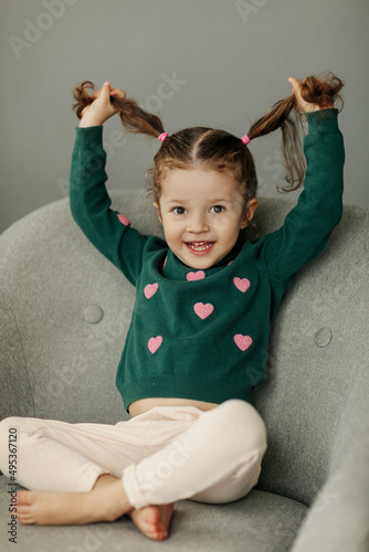 Portrait of a charming little girl with two ponytails, joyful and smiling