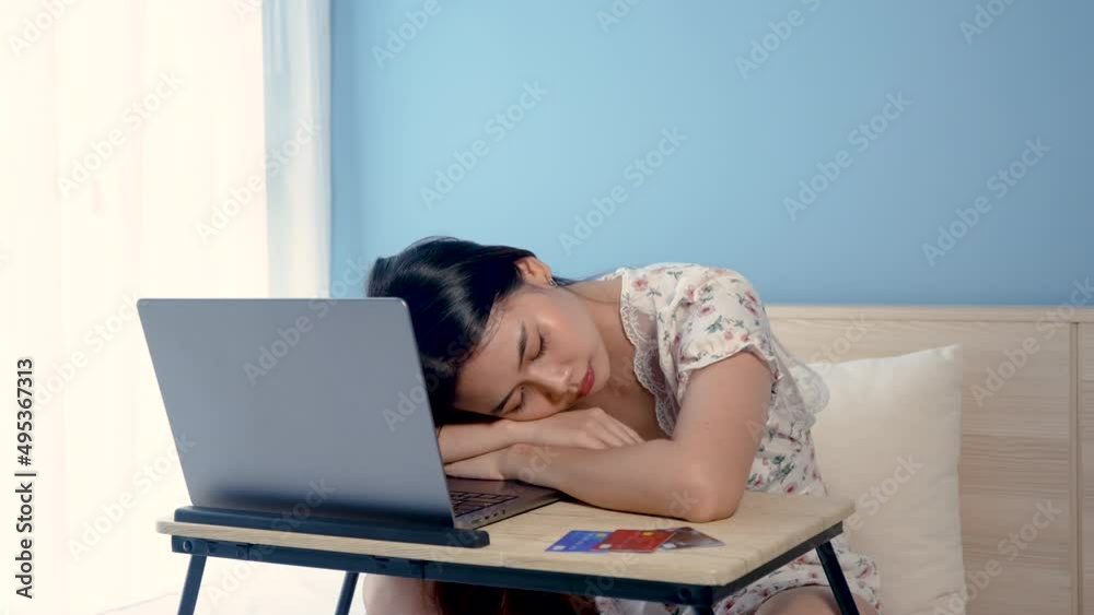 4K 50fps, adorable Asian woman falling asleep on the arm on table in front of a laptop computer after a tiring day at work in bed in the bedroom, concept, work from home 4K 50fps, adorable Asian woman falling asleep on the arm on table in front of a laptop computer after a tiring day at work in bed in the bedroom, concept, work from home