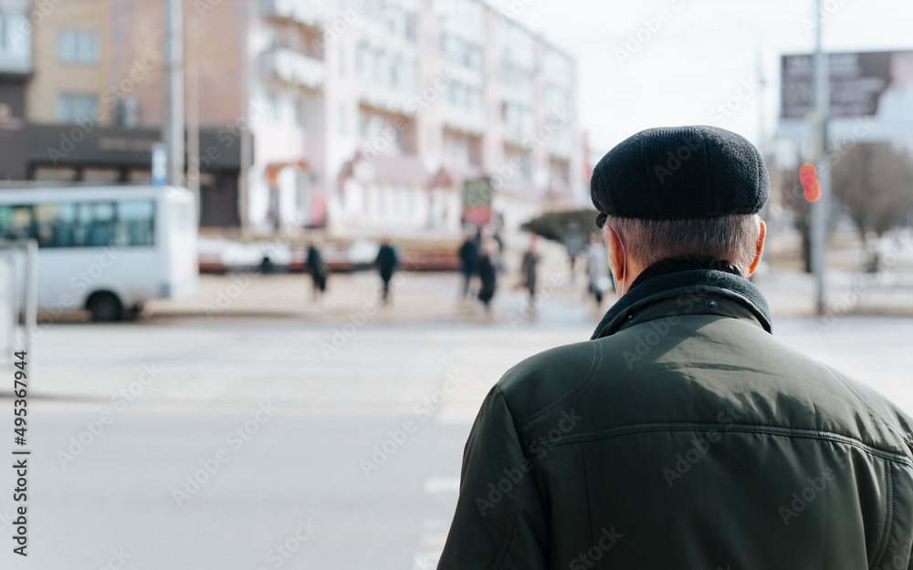 Rear view of senior man in cap and jacket standing on street, grandfather walking outdoors during day. Close-up, copy space Rear view of senior man in cap and jacket standing on street, grandfather walking outdoors during day. Close-up, copy space