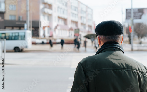 Rear view of senior man in cap and jacket standing on street, grandfather walking outdoors during day. Close-up, copy space © Sergio