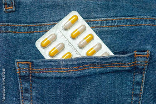 package, a blister with pills is in the back pocket of blue jeans. The concept of a serious illness and vital medicines that a person should always have with him.