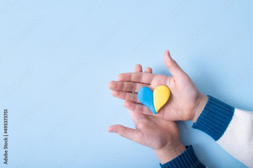 Heart of yellow-blue colors of the national flag of Ukraine in a childs hands, top view Heart of yellow-blue colors of the national flag of Ukraine in a childs hands, top view