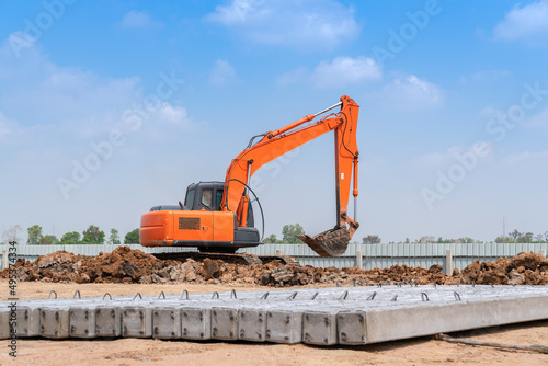 Excavator dig soil for adjust ground and pile of concrete plie