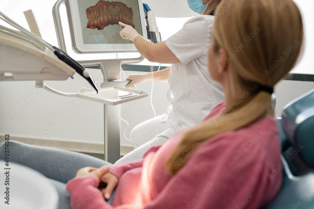 Dentist explaining teeth image on computer screen to patient in dental clinic Dentist explaining teeth image on computer screen to patient in dental clinic