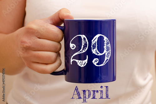 The inscription on the blue cup 29 april. Cup in female hand, business concept