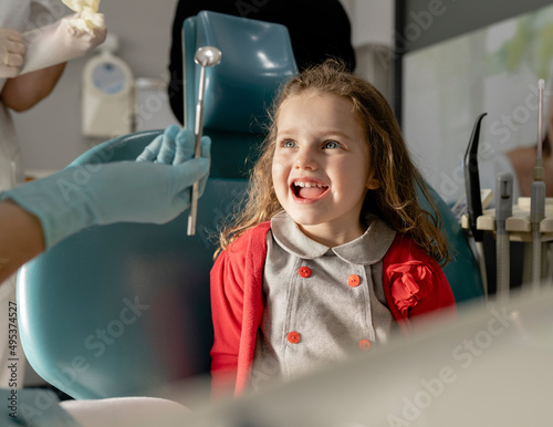 Cute little girl sitting on dentist's chair at clinic photo