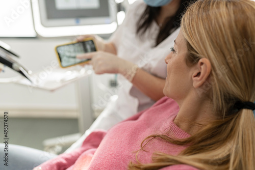 Dentist explaining x-ray image on mobile phone to patient at dental clinic photo