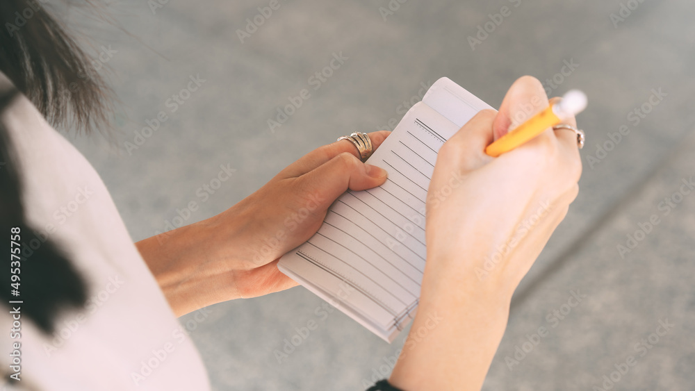 Close up business woman hand writing memo on note paper. Close up business woman hand writing memo on note paper.