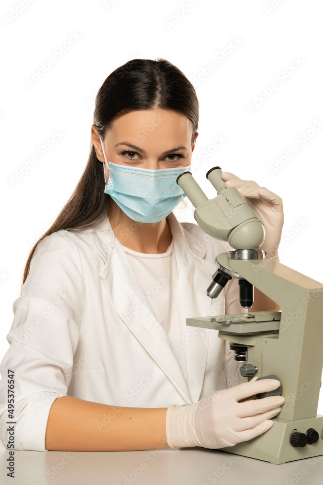 Portrait of smiling female scientist with microscope and face mask Portrait of smiling female scientist with microscope and face mask