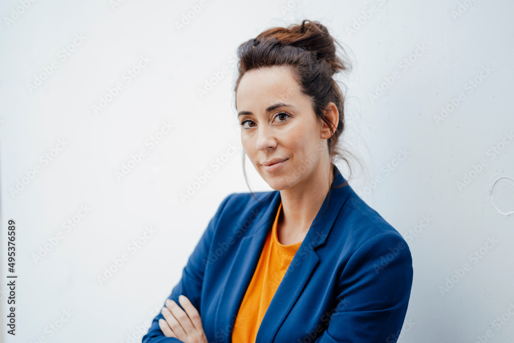 Businesswoman with arms crossed in front of white wall Businesswoman with arms crossed in front of white wall