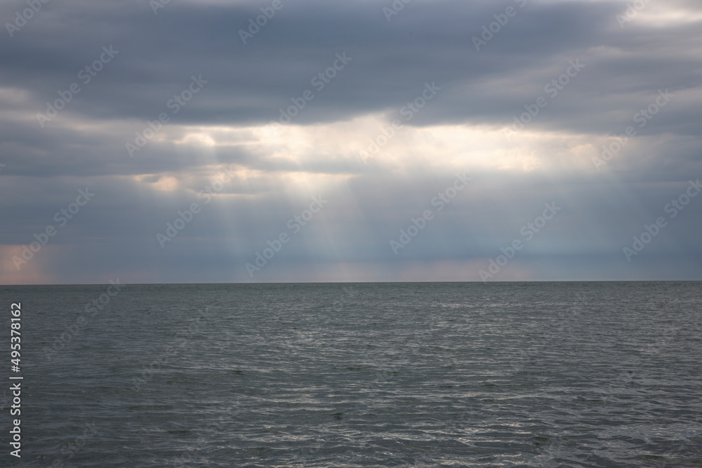 Calm seascape with stormy sky where sun-rays get through the clouds. Calm seascape with stormy sky where sun-rays get through the clouds.