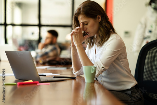 Beautiful businesswoman in office. Tired woman having headache while working..