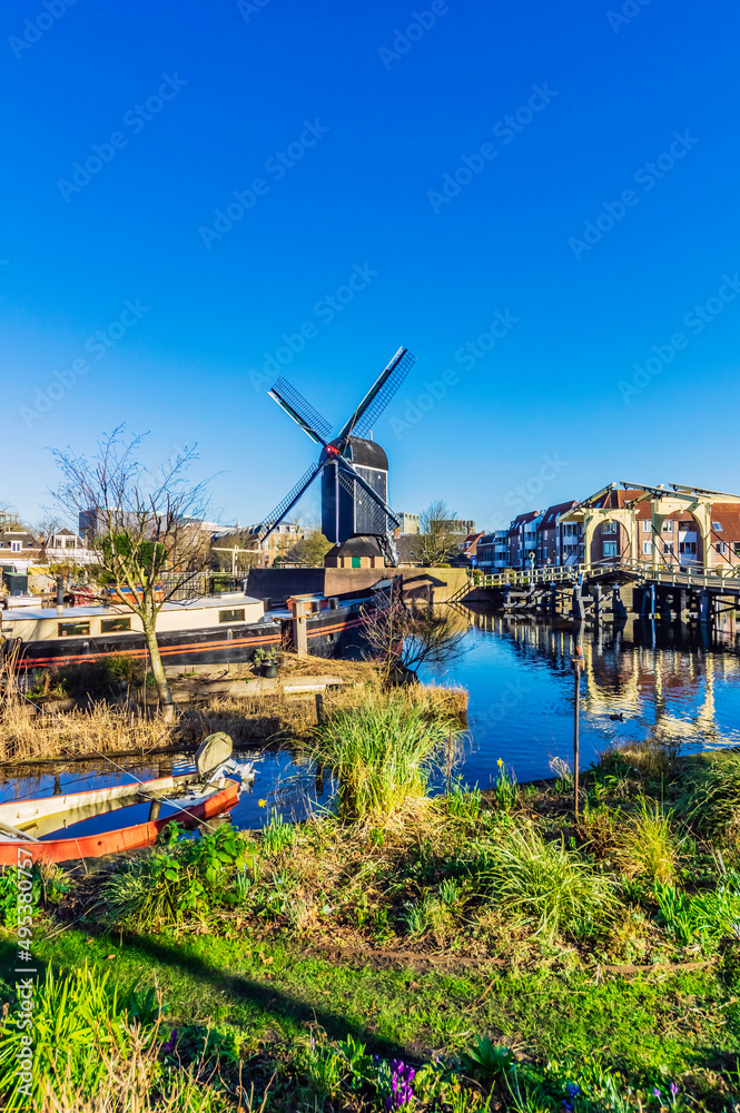 Netherlands, South Holland, Leiden, Clear blue sky over city canal with traditional windmill in background Netherlands, South Holland, Leiden, Clear blue sky over city canal with traditional windmill in background