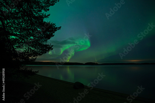 Northern lights dancing over calm lake in Farnebofjarden national park in north of sweden