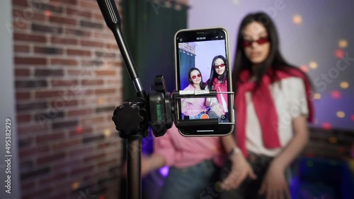 Girls dance on a smartphone camera. A view of the phone screen standing on a tripod. Social network. Blogger.