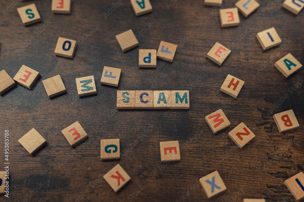 Obraz premium SCAM - a word put together with aligned wooden blocks with letters security and safety concept . High quality photo
