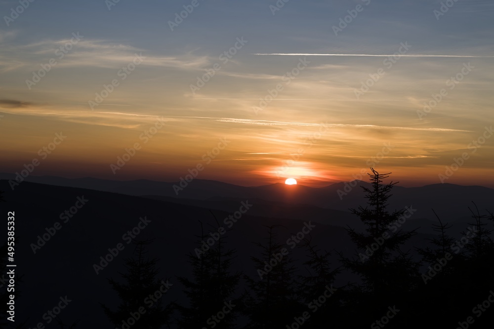 Sunrise in the mountains. In the foreground silhouettes of trees. Beautifully colored sky. Central Europe, Czech Republic, Lysá Hora.