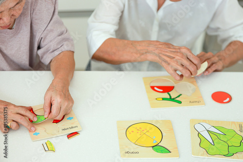 Asian senior woman holding jigsaw puzzle pieces,old elderly playing a  jigsaw puzzle games with her friend,leisure activities,development of brain,prevent Alzheimer\'s disease and dementia problems