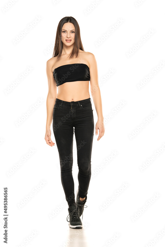 Front view of a young woman in black jeans and short top walking on a white background Front view of a young woman in black jeans and short top walking on a white background