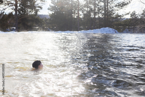 a girl in a circle swims in salt water in winter, clouds of steam rise above hot water in a salt spring of healing, nature in contrast