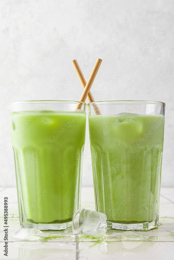 Iced green matcha latte in glasses with a straw on white background. Cold summer drink. vertical orientation Iced green matcha latte in glasses with a straw on white background. Cold summer drink. vertical orientation