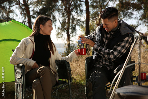 Couple resting in camping chairs and enjoying hot drink outdoors © New Africa