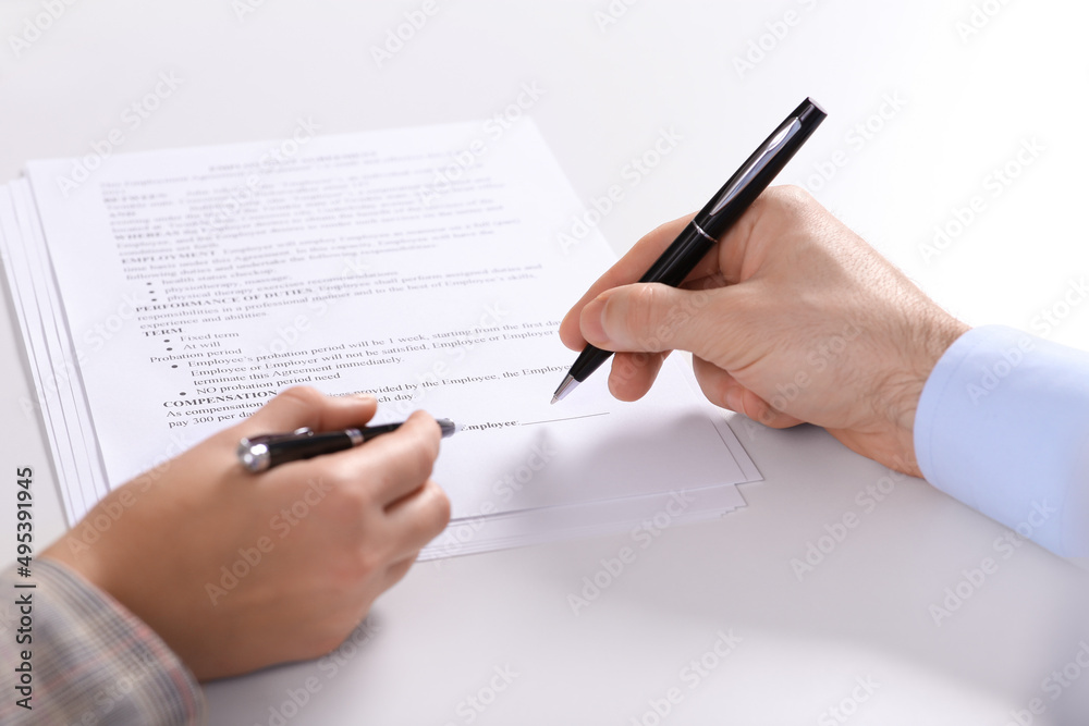Businesspeople signing contract at white table, closeup of hands Businesspeople signing contract at white table, closeup of hands