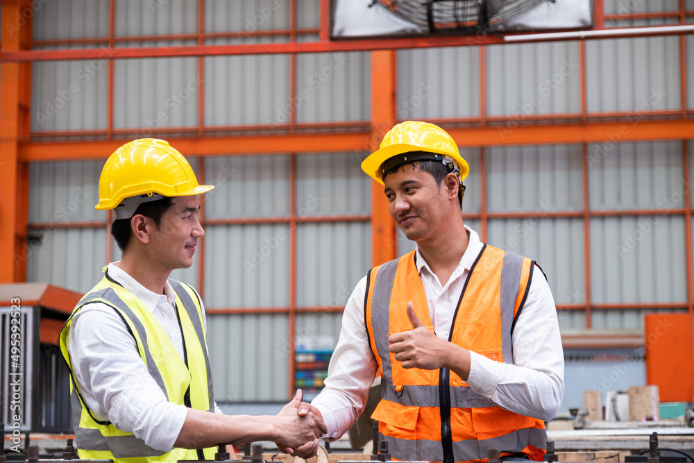 Selective focus at Asian men mechanical engineer, wearing safety equipment. While doing machine maintenance and safety control inside of factory area. With blurred background of heavy machine. Selective focus at Asian men mechanical engineer, wearing safety equipment. While doing machine maintenance and safety control inside of factory area. With blurred background of heavy machine.