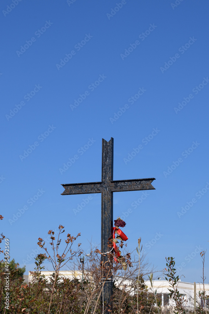 Jesus Christ cross on a blu sky background with plants, clouds and sunbeams. Easter, resurrection concept. Christian cross of God at the field on the rays of the sun outdoor. Religion background