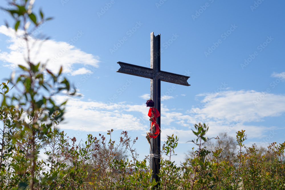 Jesus Christ cross on a blu sky background with plants, clouds and sunbeams. Easter, resurrection concept. Christian cross of God at the field on the rays of the sun outdoor. Religion background Jesus Christ cross on a blu sky background with plants, clouds and sunbeams. Easter, resurrection concept. Christian cross of God at the field on the rays of the sun outdoor. Religion background