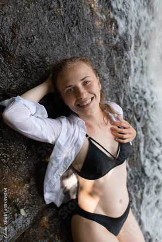 Attractive girl posing near a waterfall in a swimsuit