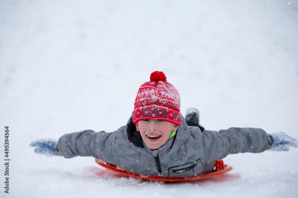 Cute young boy smiling while he is sledding Cute young boy smiling while he is sledding