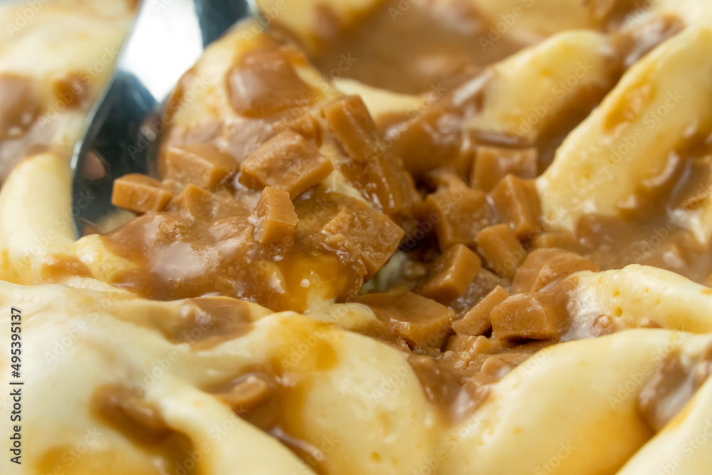 Close-up of scooping caramel ice cream with a dessert spoon. Macro photography of ice cream with caramel. Close-up of scooping caramel ice cream with a dessert spoon. Macro photography of ice cream with caramel.
