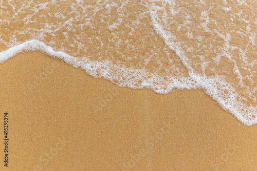 Beach sand sea water summer background. Sand beach desert texture. White foam wave sandy seashore top view