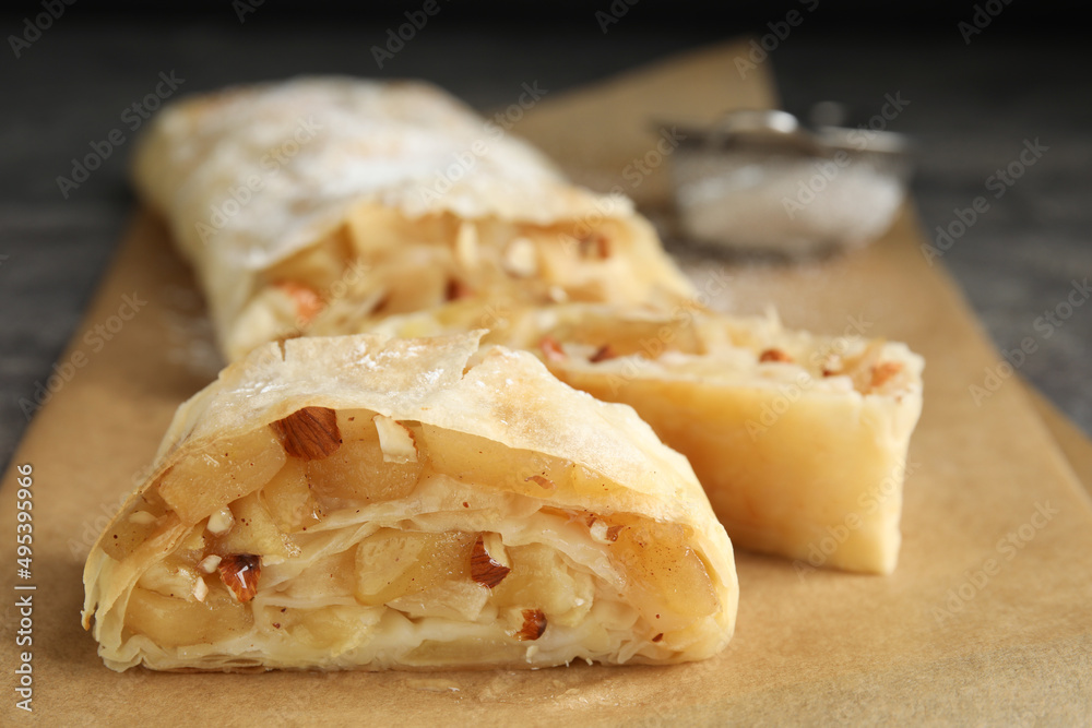 Delicious apple strudel with almonds on parchment, closeup