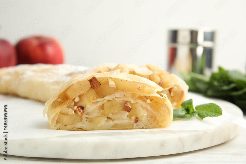 Delicious apple strudel with almonds and mint on white board, closeup Delicious apple strudel with almonds and mint on white board, closeup