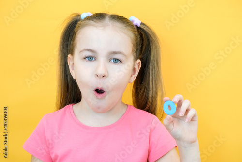 speech therapy. Toddler girl holding the letter O in her hands. Classes with a speech therapist. Girl on isolated yellow