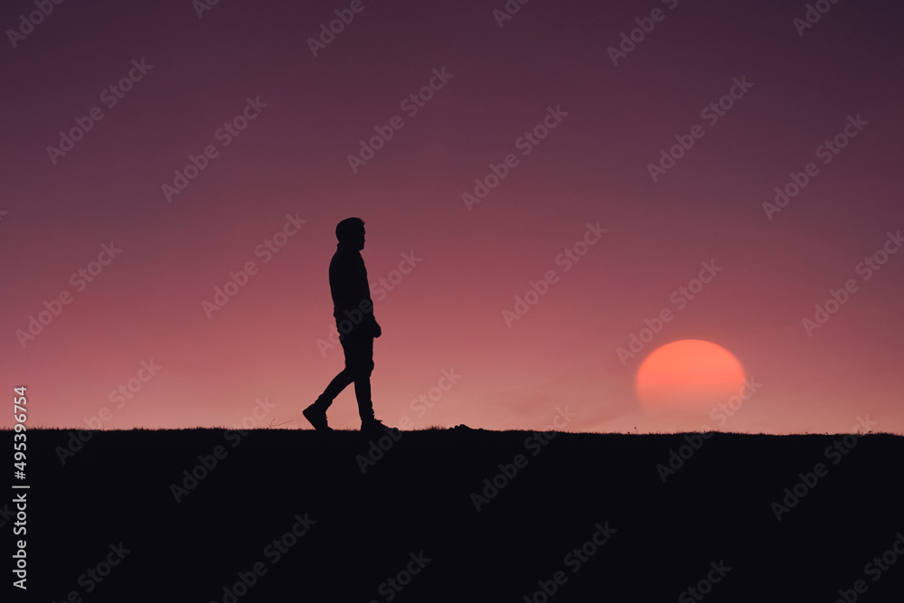 adult man silhouette in the mountain with a romantic sunset background