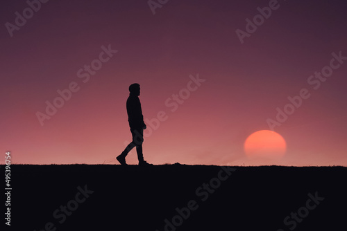 adult man silhouette in the mountain with a romantic sunset background