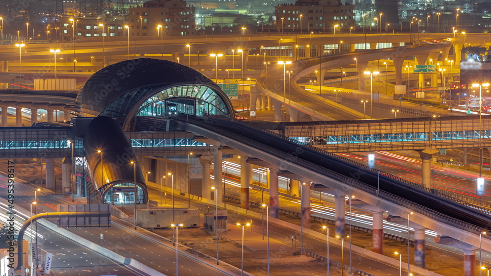Futuristic building of Dubai metro station and big junction behind in Dubai Marina aerial night timelapse