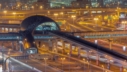 Futuristic building of Dubai metro station and big junction behind in Dubai Marina aerial night timelapse