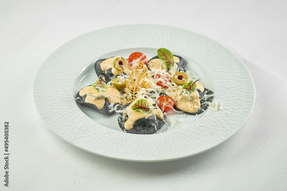 Black ravioli with red fish, sauce and tomatoes in a plate Black ravioli with red fish, sauce and tomatoes in a plate