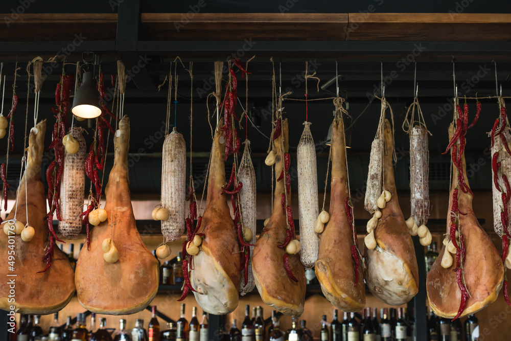 Naklejka premium Dry and salty jamon legs hanging on a bar counter