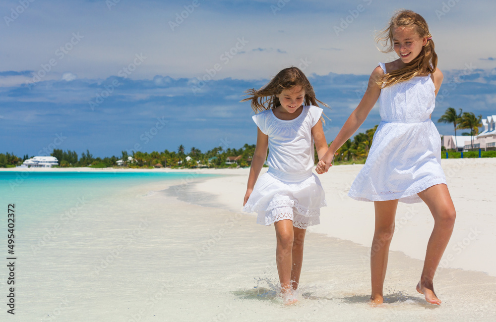Happy Caucasian female children walking in tropical beach