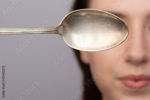 Obraz na płótnie Closeup of a woman using a cold spoon to depuff her undereye area in the morning. w salonie