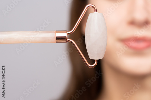 Obraz na płótnie Closeup of a woman using a rose quartz roller to depuff her face in the morning. w salonie