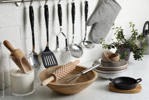 Different cooking utensils and plant on countertop in kitchen