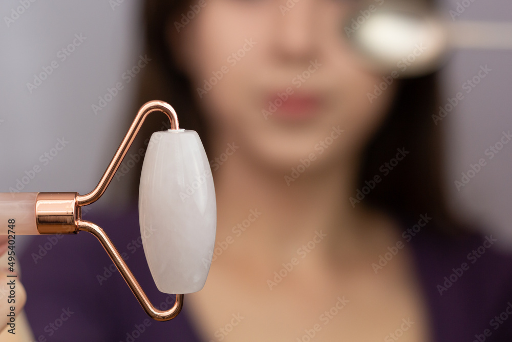 Closeup of a rose quartz roller and a cold spoon – tools that can be used to depuff face in the morning.