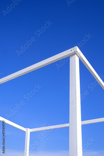 Simplicity summer background of white transparent cubic stand structure for travel photography against blue sky in vertical frame