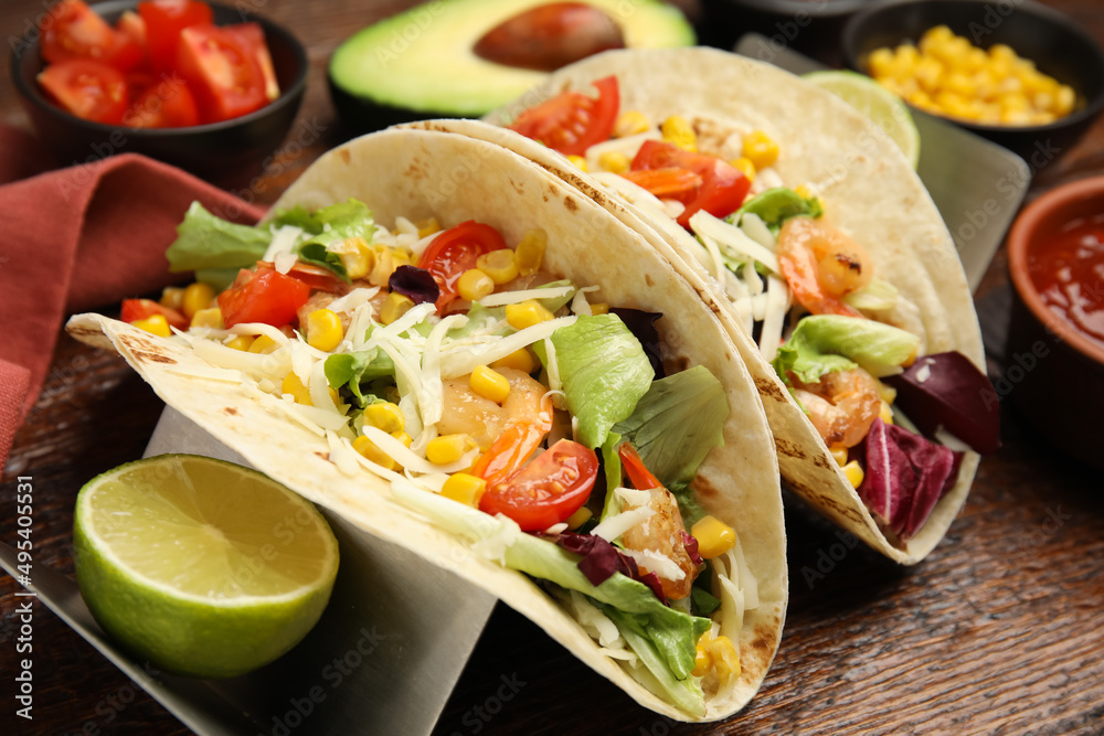 Delicious tacos with shrimps, cheese and lime on wooden table, closeup Delicious tacos with shrimps, cheese and lime on wooden table, closeup
